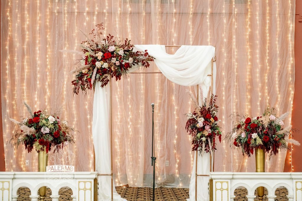 fall wedding ceremony copper structure backdrop with draping and floral accents