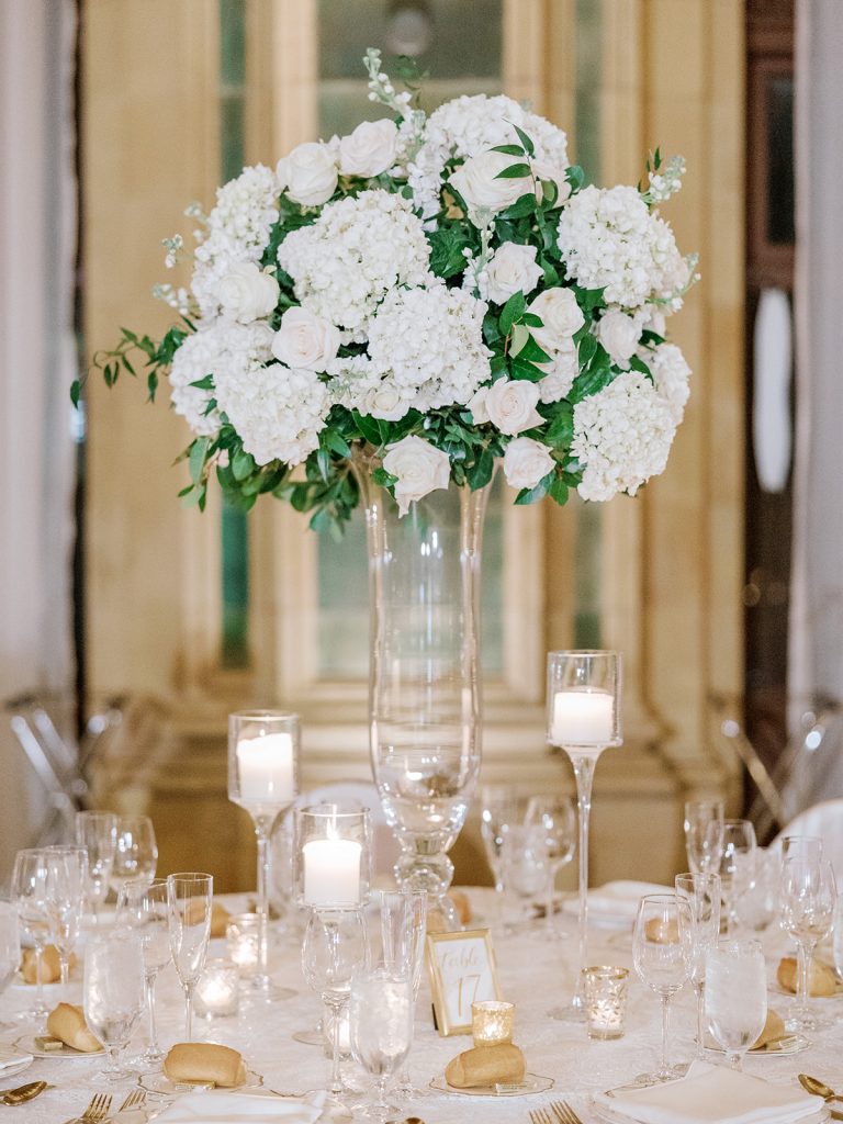 timeless elegant tall guest table centerpiece clear glass vase white flowers greenery