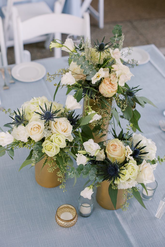 cool toned summer wedding light blue table linen gold cylinder trio floral centerpiece