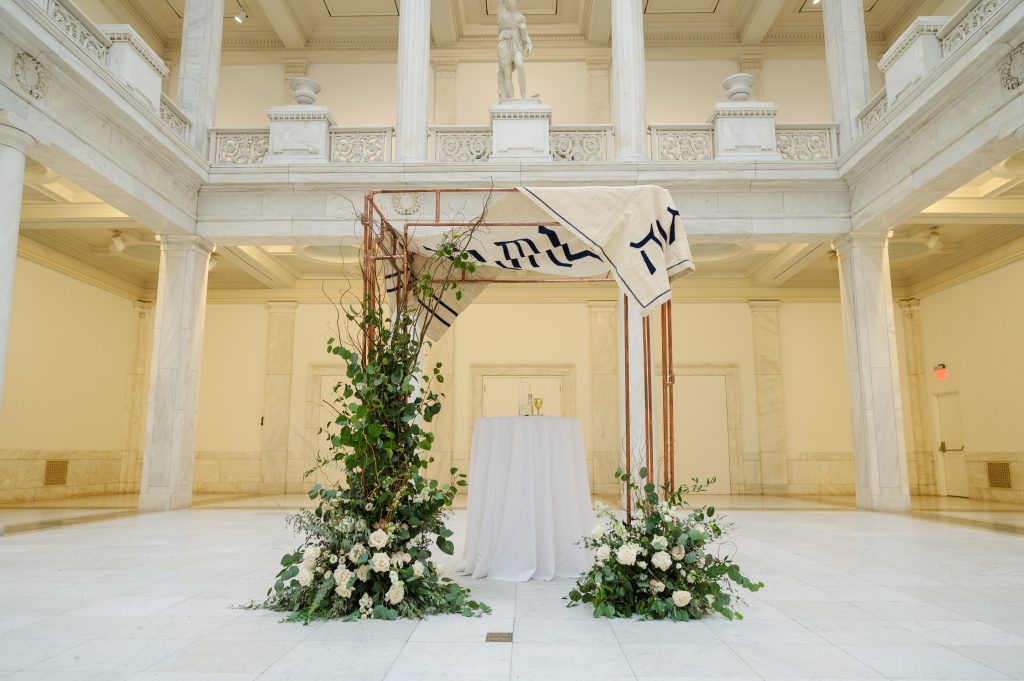 Jewish wedding ceremony Chuppah with white flowers and greenery in Carnegie Museum Hall of Sculpture Pittsburgh