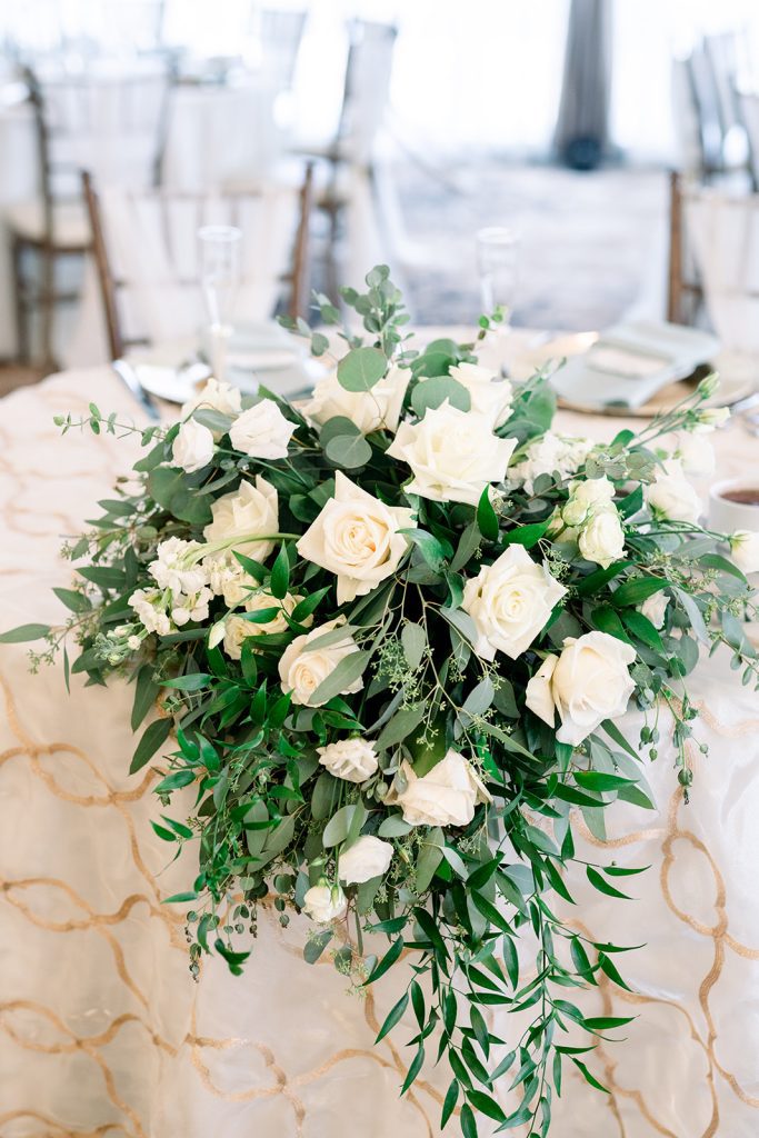 elegant bright wedding reception sweetheart table floral cascade white flowers with greenery