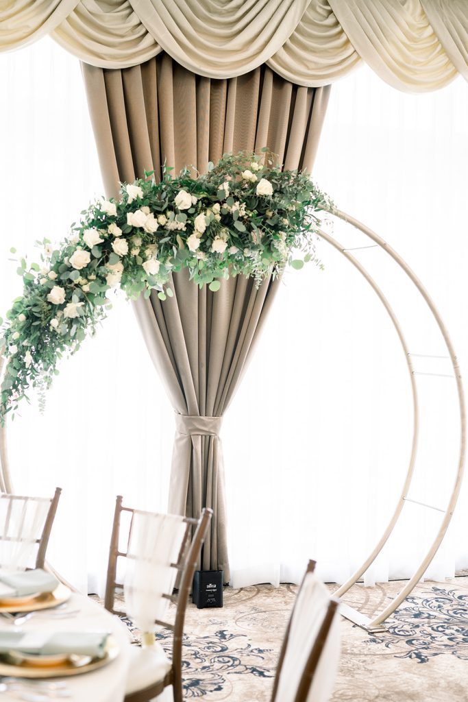 gold moon arch wedding reception decor with greenery and white flowers