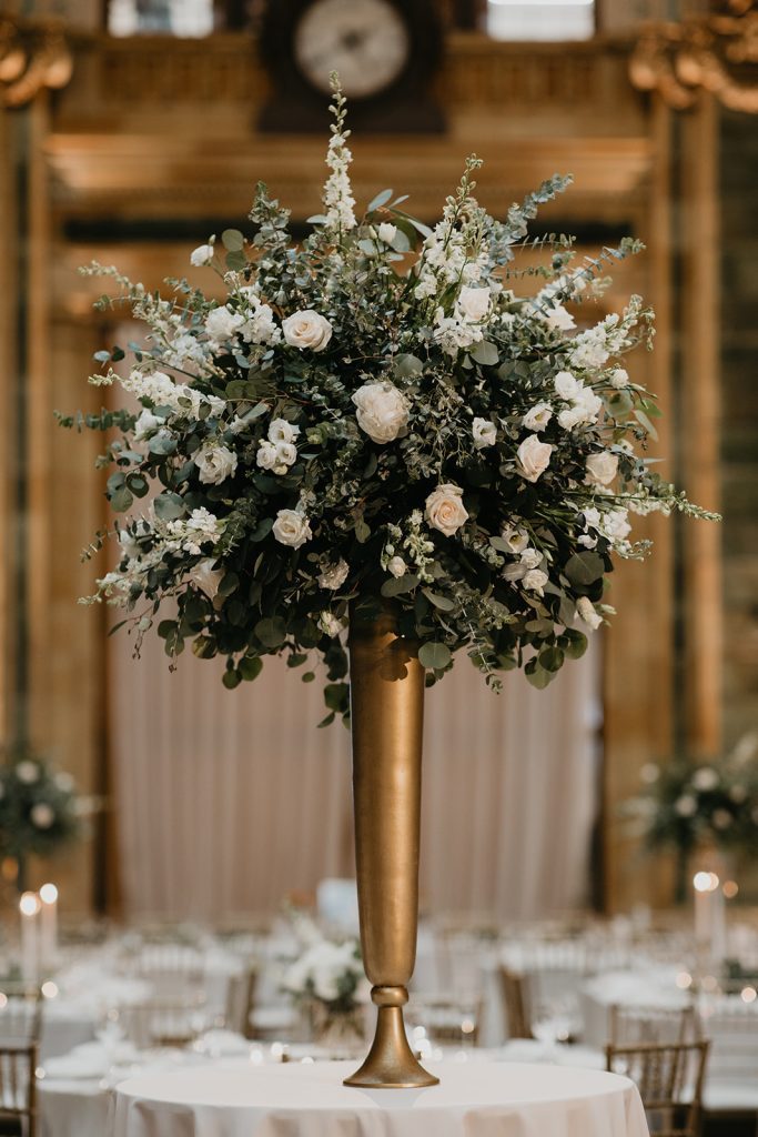 Showstopper tall centerpiece design with eucalyptus and white flowers on modern gold stand