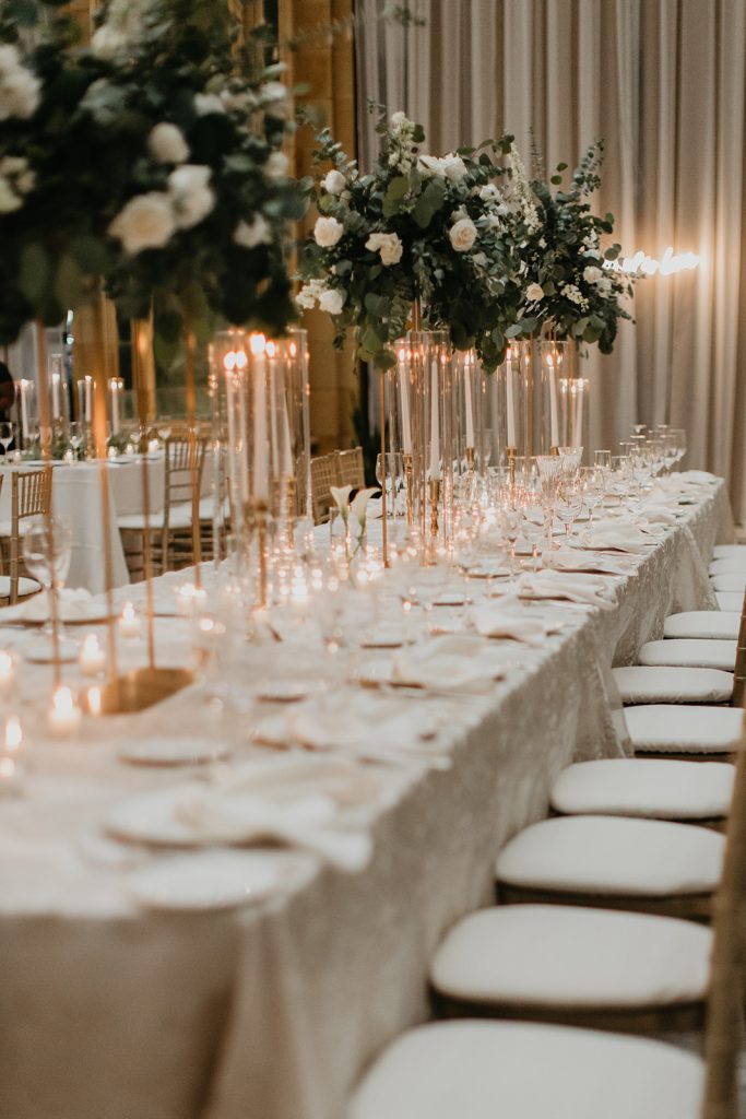 wedding reception head table with tall modern centerpieces and various candle accents